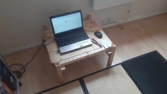 A short table with a laptop on it and a tatami mat by it