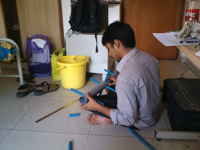 Manjunath working on assembling the blue crossbar pipes onto the gray central support pipe