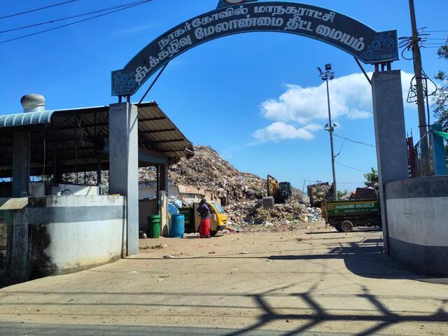 A giant dump site at a "Nagercoil Corporation Solid Waste Management Centre". Workers are seen processing the waste using earth movers and trucks.